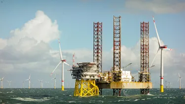 Epic Edge View on Large Offshore 8MW Wind Turbines, Wind Farm on the Horizon in the North Sea with Jack-up Boat and Offshore Platform in Wavy Sea