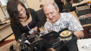 Frau gibt in einem Repair Café ihr Wissen zur Reparatur an einen Mann weiter