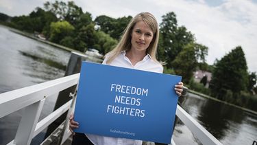 Junge blonde Frau hält ein Schild mit der Aufschrift "Freedom needs Fighters"
