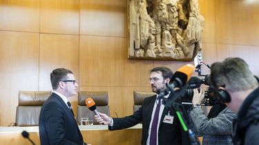 ZDF reporter and cameraman interview a male person in a courtroom