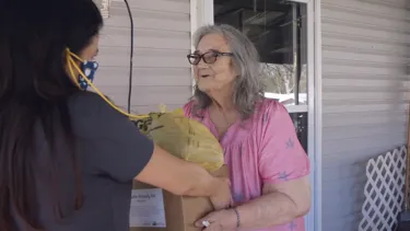 A woman gives donations in kind to an elderly woman in need