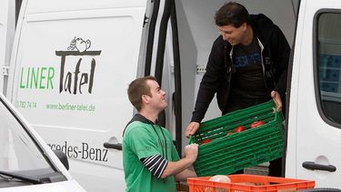 Zwei männliche Freiwillige beladen einen Lieferwagen mit Lebensmitteln