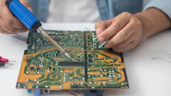 Technician using a soldering iron to repair a circuit board