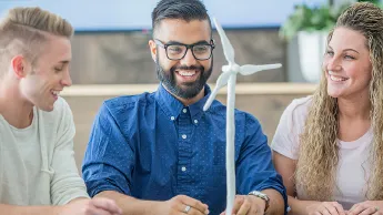 Three young people with a model of a wind turbine