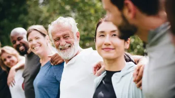 Group of people of different ages and nationalities putting their arms around each other