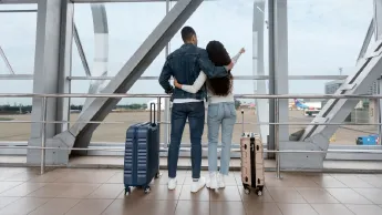 Couple looking out the window in the airport and pointing away