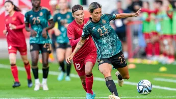 Duel on the ball between a female German football player and the opposing team.