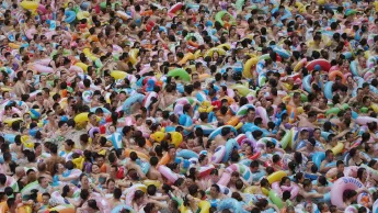 Scene from the film adaptation of the book "Capital in the Twenty-First Century": A lot of people standing very close together in a pool