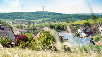 Landschaft mit Windrädern und Solaranlagen auf Hausdächern