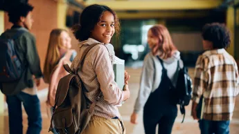 High school student walking through hallway with her friends