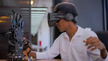 Junger dunkelhäutiger Student arbeitet mit Roboterarm-Projekt und Virtual Reality.