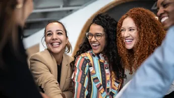 Smiling women with stacked hands at the office.