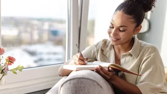 Young African-American women writes in her notebook.