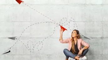 Junge Frau mit einem Papierflugzeug in der Hand