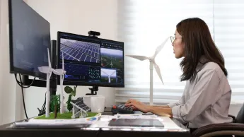 Woman sits at the computer and plans sustainable energy concepts (wind power and solar).