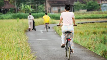 Cyclist in rural Asia symbolizes sustainable transport in Indonesia