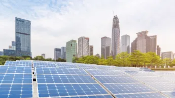 Nachhaltige Stadt: Skyline der Stadt Shenzhen in China im Hintergrund und großes Solarpanel im Vordergrund