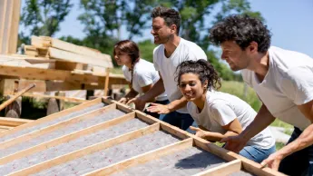 A group of young volunteers help build a house