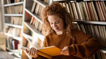 Junge Frau liest ein Buch in der Wohnung