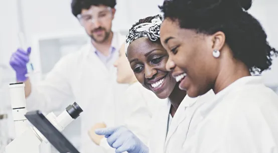 Three people in a medical work environment in front of a microscope