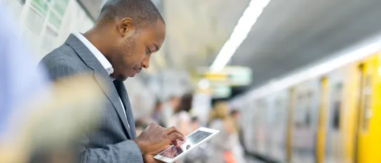 Junger Mann liest Online-Magazin auf einem Tablet in der Bahn