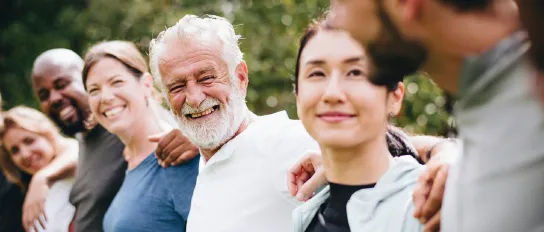 Group of people of different ages and nationalities putting their arms around each other