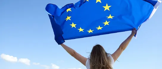 Eine junge blonde Frau hält eine Europa-Flagge in die Luft