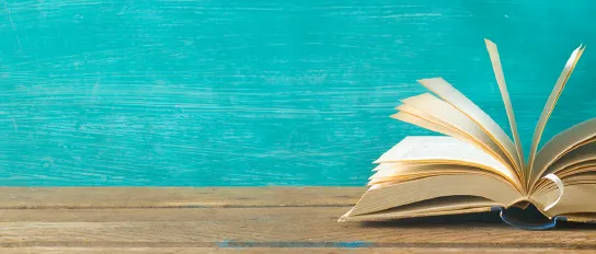 Open book in front of a turquoise wall